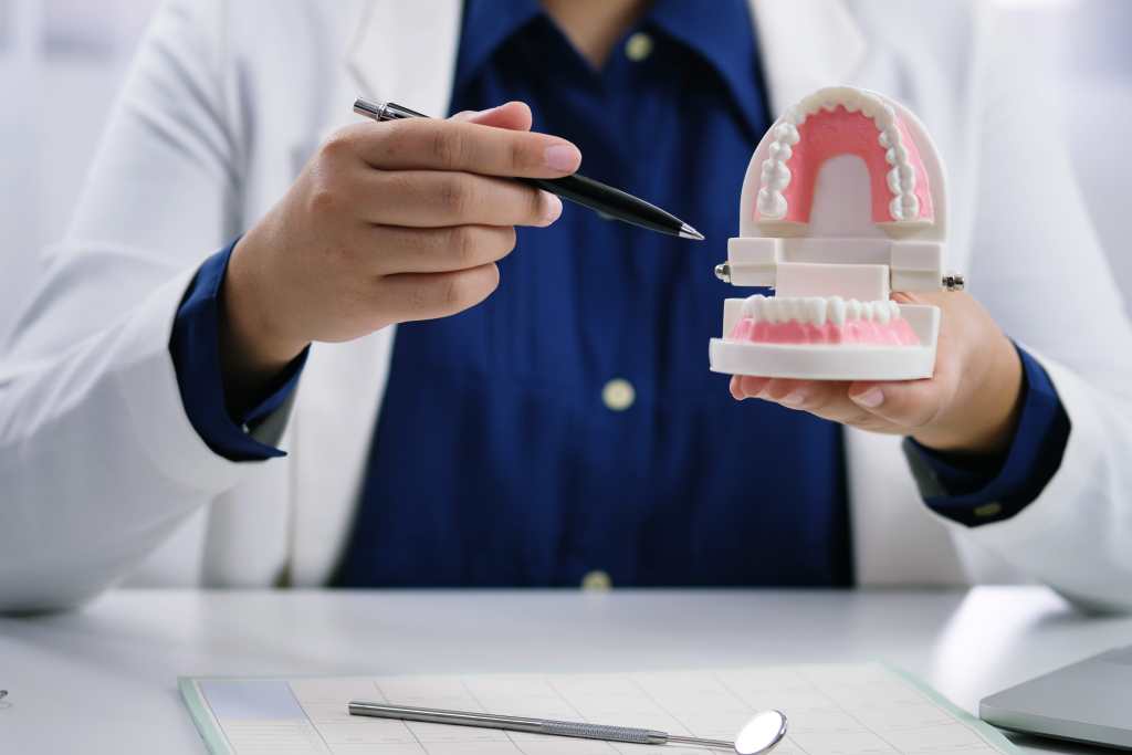 dentist explaining and holding dentures